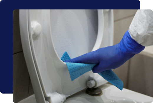 Janitor wiping down a toilet during commercial restroom cleaning